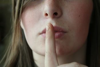 Image of a Woman Holding Her Finger to Her Lips, Representing How to Find Hidden Assets in a NJ Divorce